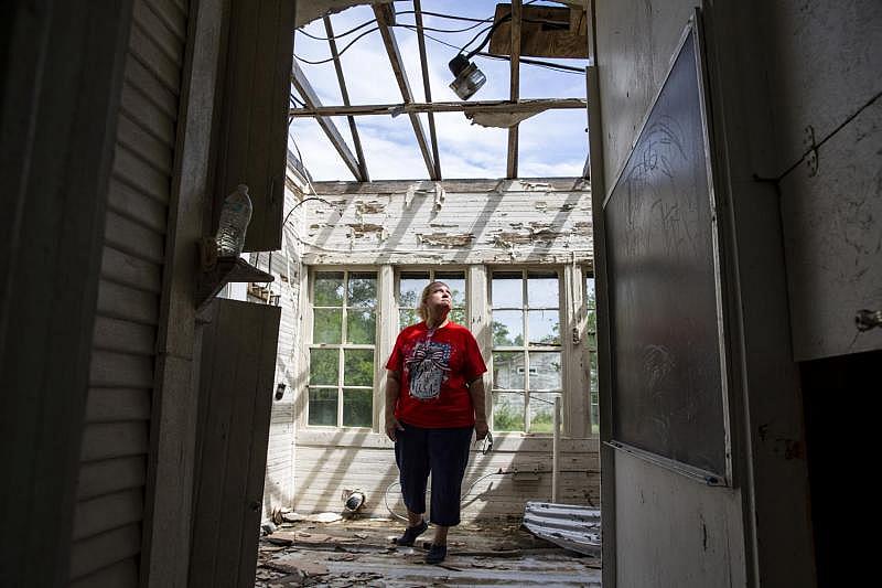 While revisiting her wrecked Bayside home, Sabine Wiegand stands in the foyer and looks up through the hole in her roof for a portrait. Town officials said about 50 homes were destroyed in the storm, driving an unknown number away permanently.