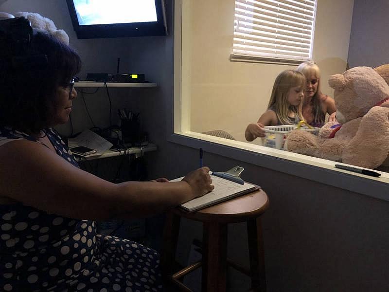 Therapist Laurie Taylor observes mother and daughter from behind the two-way mirror. (Laura Klivans/KQED)