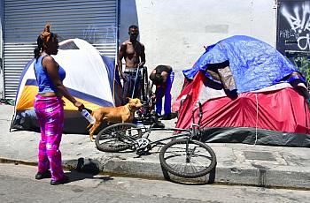 Homeless residents chat beside their tents on a street in downtown Los Angeles, California on June 25, 2018.