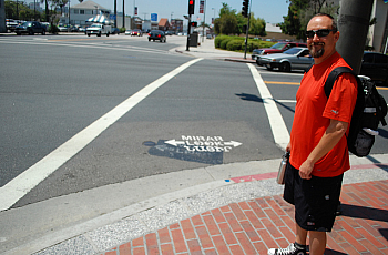 Glendale PLACE Grant Coordinator Colin Bogart shows off the new tri-lingual pedestrian safety markings at an intersection adjace