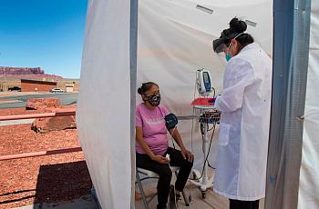 A nurse checks vitals on a Navajo woman complaining of virus symptoms at a COVID-19 testing center in Monument Valley, Arizona i