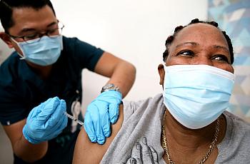  Lorraine Harvey, an in-home care worker, receives her first dose of the COVID-19 vaccine