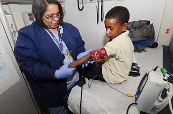Tanisha Jones checks the blood pressure of Derrick Jenkins, 7, aboard a mobile clinic outside Dixon elementary school. (Photos by Max Ortiz / The Detroit News)  