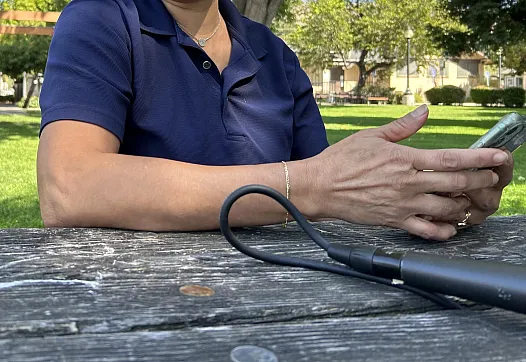 Image of a person sitting across the table in a park using their phone