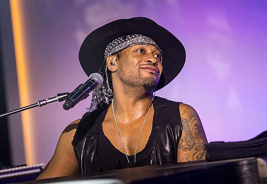 Person with hap and black top in front of a mic