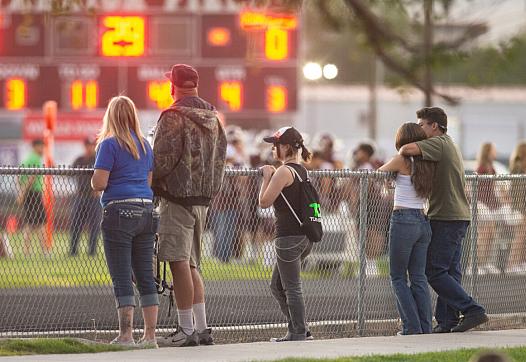 People watch a football game over a fence