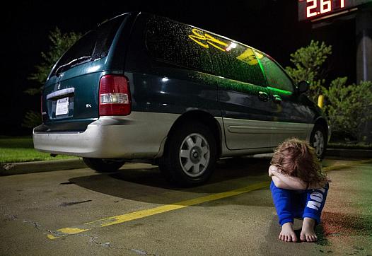 In a Victoria motel parking lot, Zoey Bowman sits on the ground and pouts in front of her mother's minivan in September.