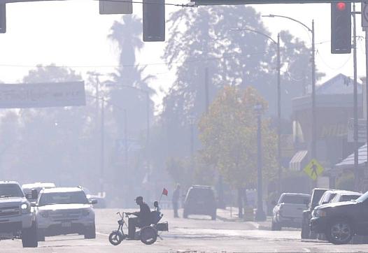 A man in a scooter rides through Old Town Clovis on a smoggy afternoon on Nov. 6, 2014.