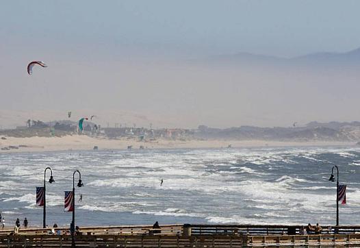 Wind brought out windsurfers south of Pismo Pier on August 21. It also contributed to a dusty haze obscuring the view.